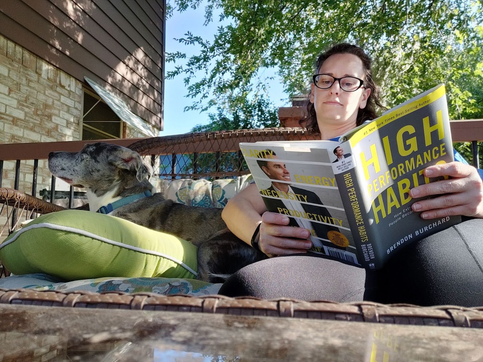 Sarah reading a magazine on her porch with her dog