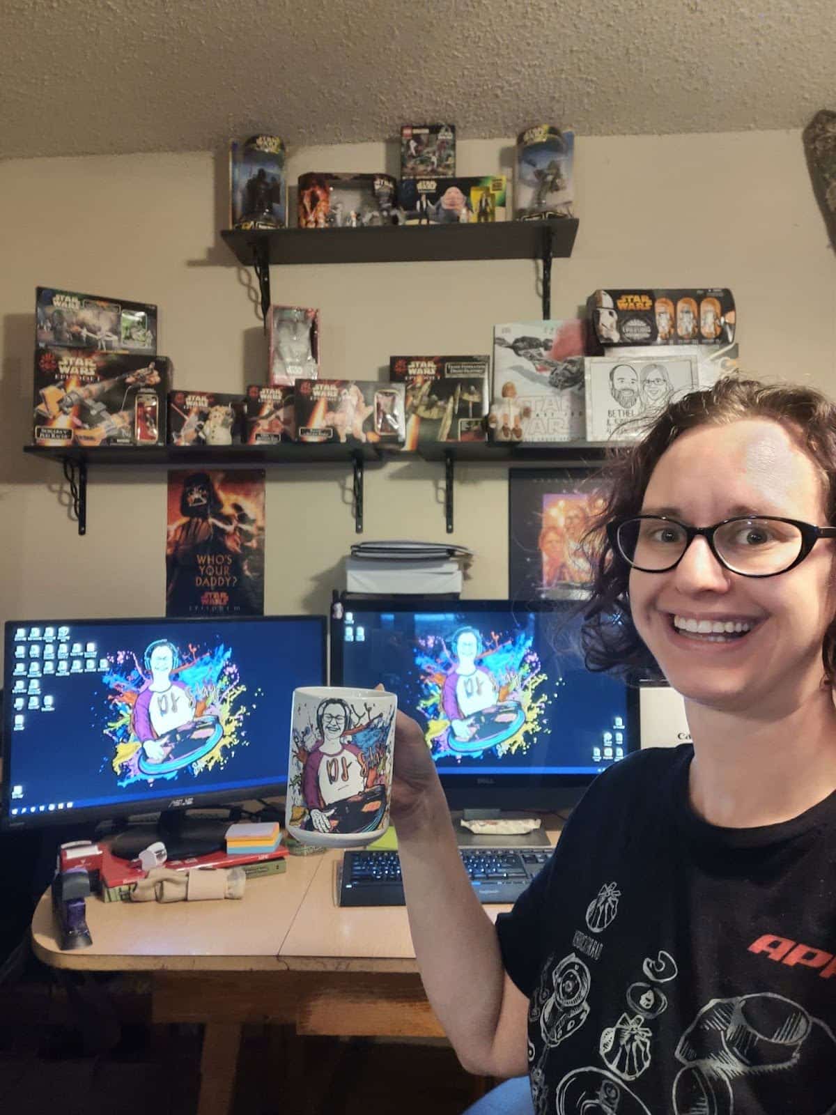Sarah holding up her customized mug in front of her workstation 